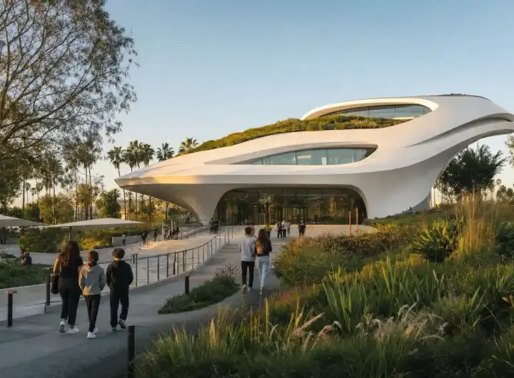 Edificio museale bianco e futuristico con tetto verde, giardini e visitatori che camminano verso l’ingresso al tramonto