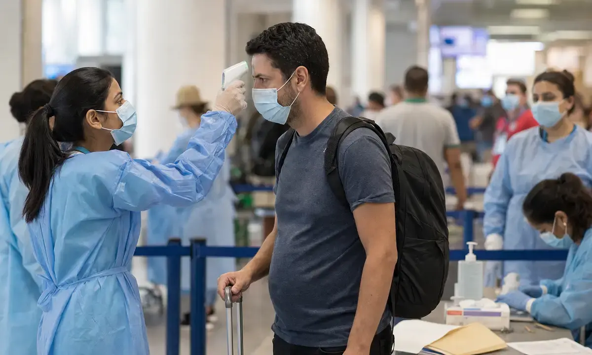 Operatrice sanitaria misura la temperatura a un viaggiatore con termometro a infrarossi in aeroporto