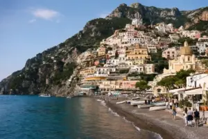 Positano sulla Costiera Amalfitana con case color pastello sul promontorio, spiaggia con barche e cupola della chiesa