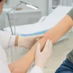 Medico con guanti esamina un lieve arrossamento sull’avambraccio di un paziente in ambulatorio
