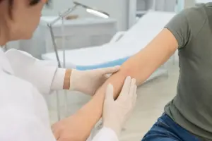 Medico con guanti esamina un lieve arrossamento sull’avambraccio di un paziente in ambulatorio