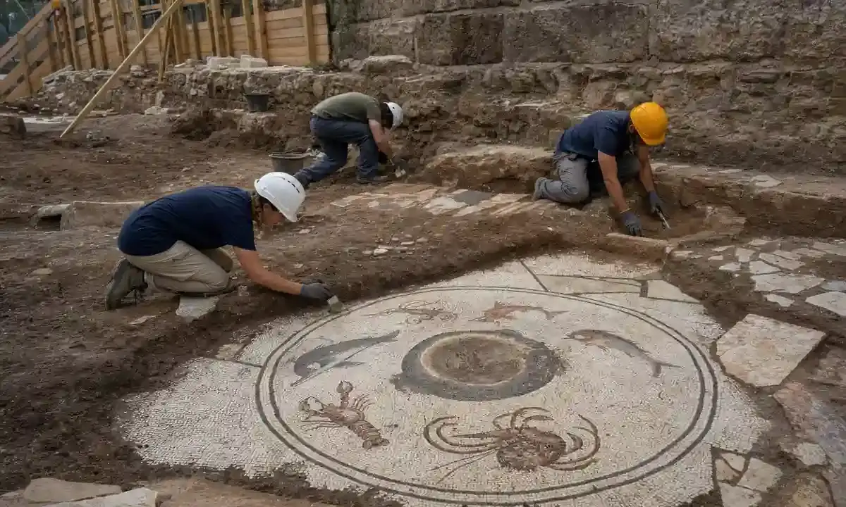 Archeologi al lavoro su un mosaico romano con delfino, pesci, aragosta e granchio in uno scavo