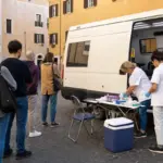 Donatori in fila accanto a un’unità mobile per la donazione di sangue in una piazza di Roma