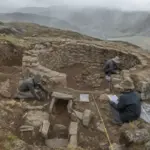 Archeologi scavano una struttura circolare in pietra sulle Ande, con metro a nastro e strumenti sul terreno
