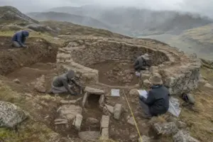 Archeologi scavano una struttura circolare in pietra sulle Ande, con metro a nastro e strumenti sul terreno